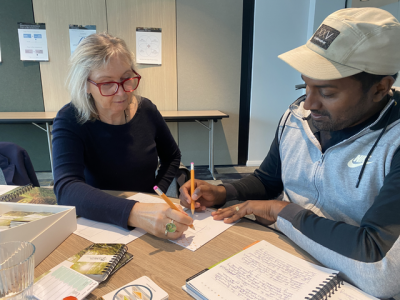 Woman and man sitting at desk writing on the same pad