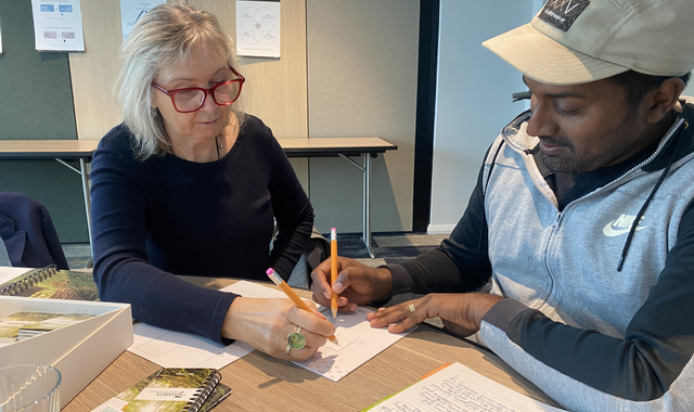 Woman And Man Sitting At Desk Writing With Pens